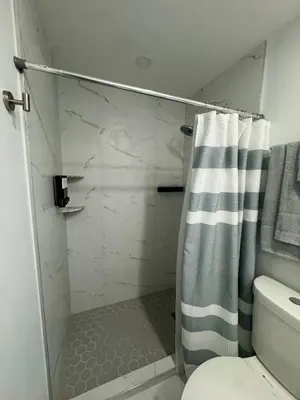 a bathroom with a shower with a striped shower curtain at Elegant Miami South Stay! in Cutler Bay