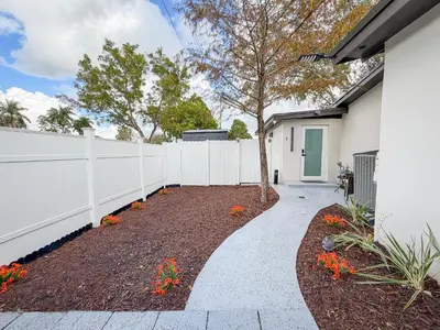 a garden with a white fence and a sidewalk at King Comfort Suite Kitchen Wi-Fi Parking in Pembroke Pines
