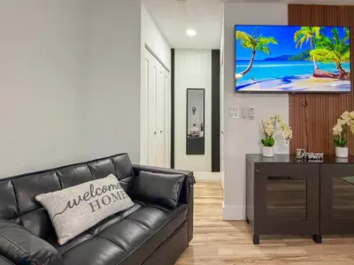 a living room with a black leather couch and a flat screen tv at King Comfort Suite Kitchen Wi-Fi Parking in Pembroke Pines