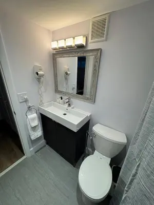 a bathroom with a toilet and a sink and a mirror at Beachfront two story apartment in Miami Beach