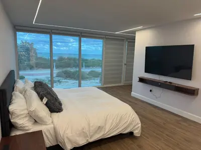 a bedroom with a large bed and a flat screen tv at Beachfront two story apartment in Miami Beach