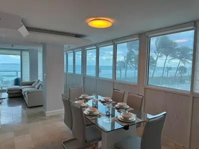 a dining room with a table and chairs with a view of the ocean at Beachfront two story apartment in Miami Beach