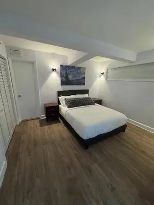 a bedroom with a white bed and wooden floors at Beachfront two story apartment in Miami Beach