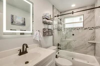 a white bathroom with a sink and a shower at 3 Mi to Port Everglades Modern Getaway with Yard in Dania Beach