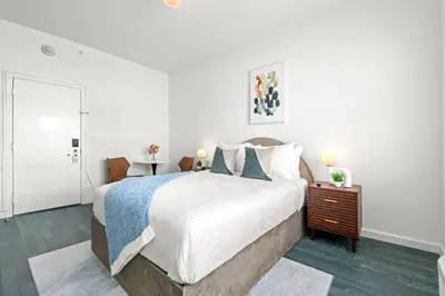 a white bedroom with a large bed and a table at Bluebird Suites at The Apex Miami in Miami Beach