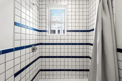 a bathroom with a shower with blue and white tiles at Bluebird Suites at The Apex Miami in Miami Beach