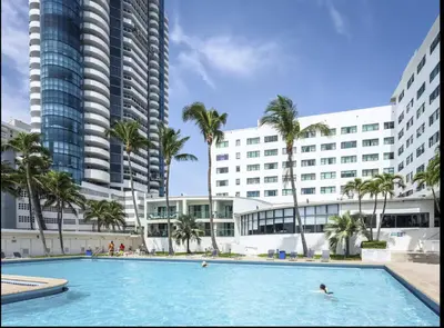 a swimming pool in front of a hotel with palm trees at Miami Beach-Front with Amazing Pool in Miami Beach