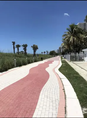 a red brick road with palm trees in the distance at Miami Beach-Front with Amazing Pool in Miami Beach