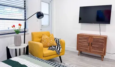 a living room with a yellow chair and a tv at The Hideaway - Wilton Manors in Fort Lauderdale