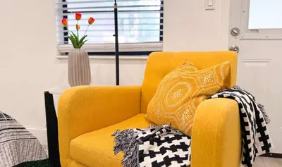 a yellow chair with pillows in a living room at The Hideaway - Wilton Manors in Fort Lauderdale