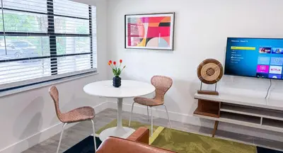 a living room with a table and chairs and a tv at The Hideaway - Wilton Manors in Fort Lauderdale