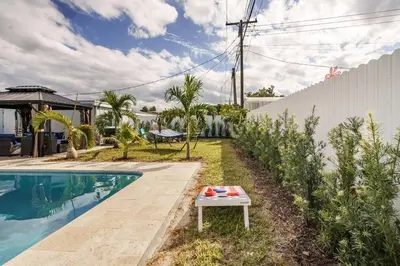 a table next to a swimming pool next to a house at 4 BR home with private pool in Fort Lauderdale
