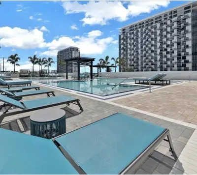 a swimming pool with picnic tables and a building at Stylish Urban 5350 Park Doral in Miami