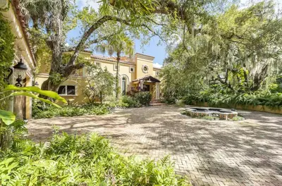 a large yellow house with trees in front of it at Serene 7000 SF Gated Luxury Waterfront Home in Fort Lauderdale