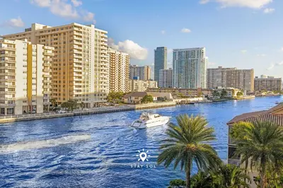 a boat in a river in a city with buildings at Apt with Private Balcony - Incredible Pool in Hallandale Beach