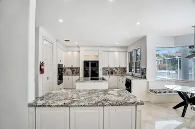 a kitchen with white cabinets and a marble counter top at 6BR Elegant Hollywood Lakes Mansion with Private Pool & Spa in Hollywood