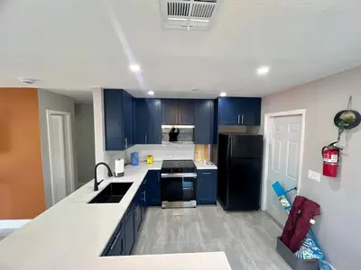 a kitchen with blue cabinets and a black refrigerator at 20 OFF Golden Hour BBQ 10 MIN Beach Airport FL in Fort Lauderdale