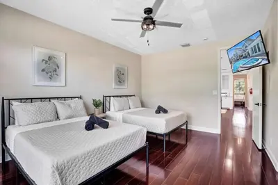 two beds in a room with a ceiling fan at 6BR Elegant Hollywood Lakes Mansion with Pool & Spa home in Hollywood