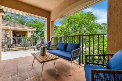 a porch with a blue couch and chairs on a balcony at Salty Fox 5BD Oasis w Spa, Beach & Downtown in Fort Lauderdale