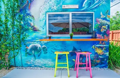 a mural on the side of a building with two stools at Private Retreat with Yard Near Hard Rock Stadium in Miramar