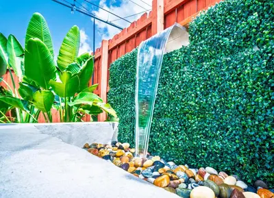 a garden with a water fountain in front of a hedge at Private Retreat with Yard Near Hard Rock Stadium in Miramar
