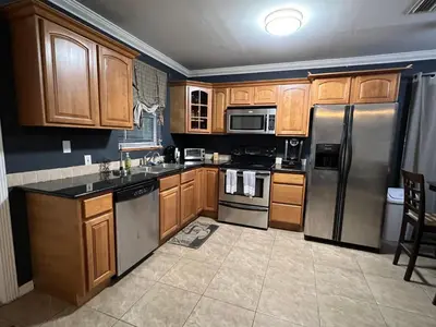 a kitchen with wooden cabinets and stainless steel appliances at Modern 2 BR near shops, WD fast WiFI 2000mbps 10 min to beach Bliss 7 in Hollywood