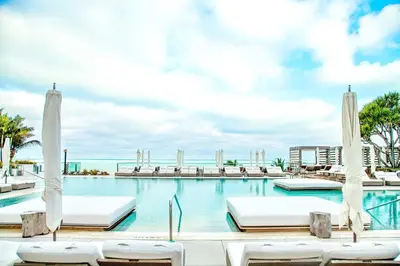 a swimming pool with chairs and umbrellas at South Beach Amazing Ocean View in Miami Beach