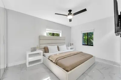 a white bedroom with a bed and a ceiling fan at Azure Coastal Breeze in North Miami Beach