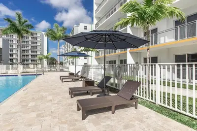 a patio with chairs and an umbrella next to a pool at Landing Incredible 3BD Pool Gym in Naranja