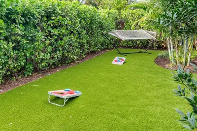 a garden with a hammock and a table on the grass at Stylish 2BR Oasis with Pool Mini Golf & BBQ in Fort Lauderdale