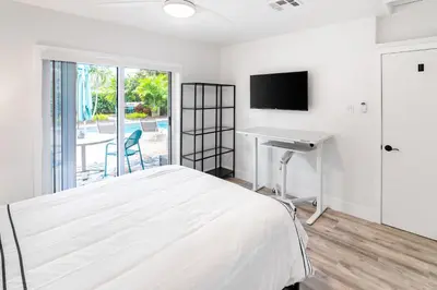 a bedroom with a bed and a desk and a television at Stylish 2BR Oasis with Pool Mini Golf & BBQ in Fort Lauderdale