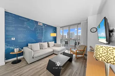 a living room with a couch and a blue wall at Amazing Apartment with Bay View Balcony Near Beach in Hallandale Beach