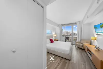 a bedroom with a bed and a desk and a window at Peaceful Bay View Apartment Near Beach in Hallandale Beach