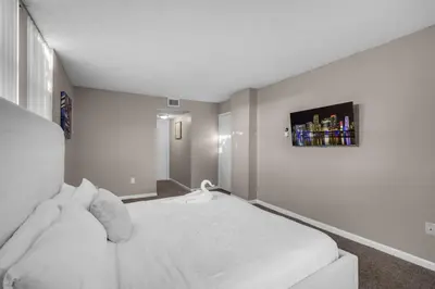 a white room with a bed and a tv on the wall at Stylish 2BR in North Miami with Free Parking in North Miami