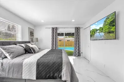a bedroom with a large bed and a tv at Oasis With Pool and Putting Green in Hollywood