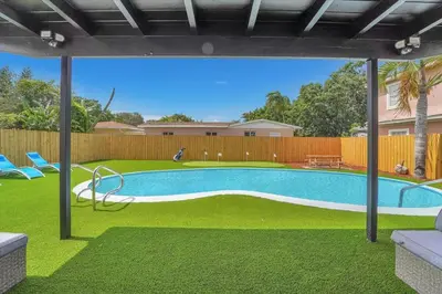 a swimming pool with green grass and a fence at Oasis With Pool and Putting Green in Hollywood