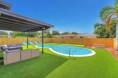 a backyard with a swimming pool and green grass at Oasis With Pool and Putting Green in Hollywood