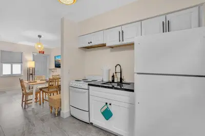 a kitchen with a white refrigerator and a table at Santorini Blu Elegant 1BR Beach Retreat On the Beach in Hollywood