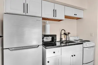 a kitchen with white cabinets and a stainless steel refrigerator at Santorini Blu Boutique Beach Studio Steps to Ocean in Hollywood