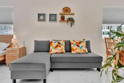 a living room with a gray couch with colorful pillows at Santorini Blu Boutique Beach Studio Steps to Ocean in Hollywood