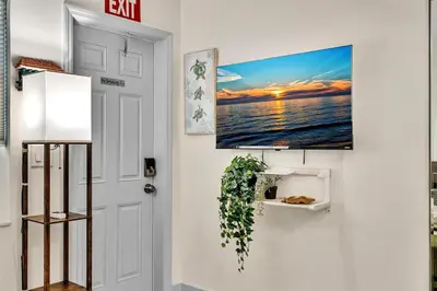 a living room with a tv hanging on a wall at Santorini Blu Stylish Coastal Studio on the Beach in Hollywood