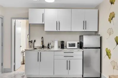 a kitchen with white cabinets and a refrigerator at Santorini Blu Stylish Coastal Studio on the Beach in Hollywood