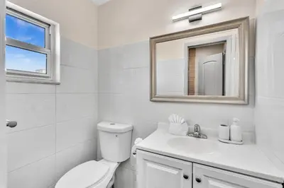 a bathroom with a toilet and a sink and a mirror at Santorini Blu Spacious 2BR Beachfront Suite in Hollywood