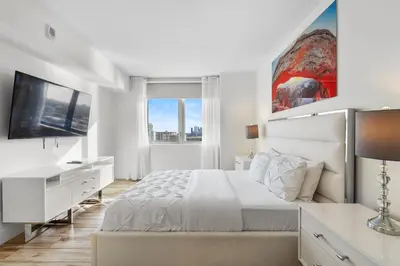 a white bedroom with a large bed and a television at Luxury Oceanview Condo with Private Foyer at Beachwalk Resort in Hallandale Beach