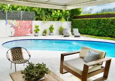 a patio with a swimming pool with a chair and a table at Luxury 4BR Coconut Grove Home wIith Pool and BBQ in Miami