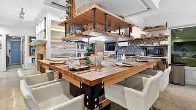 a kitchen with a large wooden table and white chairs at Casa Pineapple Social by AvantStay Spa Game Room EV Charger Near Las Olas Fort Lauderdale Beaches Sleeps 16 in Fort Lauderdale
