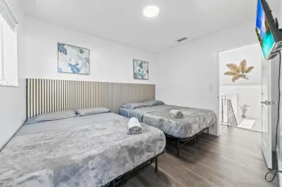 two beds in a room with white walls and wooden floors at Casa Sol - 4 Bedroom 2 Bath - 7 beds - Affordable Stays For Large Groups in Ives Estates