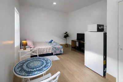 a room with a bed and a table and a refrigerator at Quiet Studio Retreat attached to big House in Miami