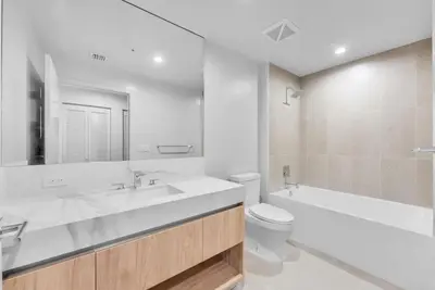 a white bathroom with a tub and a toilet and a sink at Chic Downtown Miami 2BR City Views Rooftop Pool in Miami