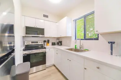 a white kitchen with white cabinets and a sink at Modern Apartment in Prime Miami Location in Miami